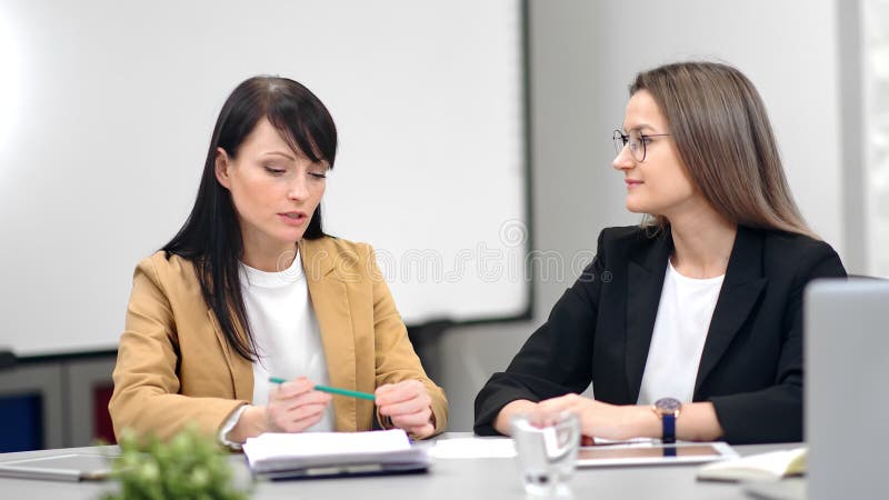 Two smiling business woman talking at office discussing work having professional job interview stock footage Two smiling business woman talking at office discussing work having professional job interview stock footage
