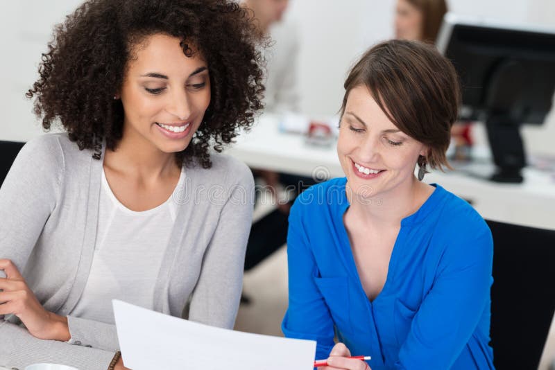 Two smiling businesswomen working on a document royalty free stock image Two smiling businesswomen working on a document royalty free stock image
