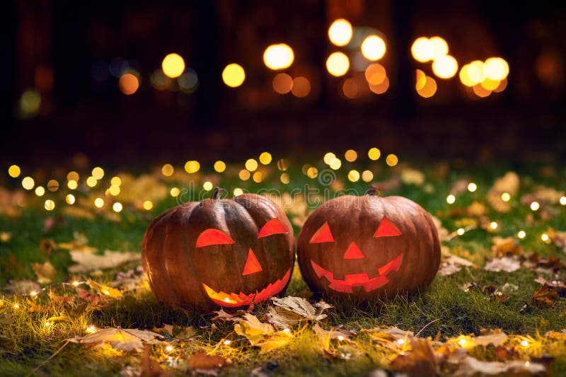 Two smiling Halloween Pumpkins on a grass with lights In A Park At Night stock photography Two smiling Halloween Pumpkins on a grass with lights In A Park At Night stock photography