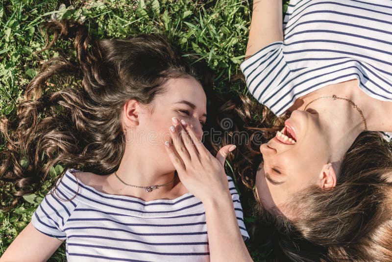 Two smiling young female girl friends having fun in park. Trendy Hipster Best friends Girls Relaxing on the Grass . Summer