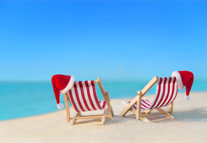 Two striped sunloungers with Christmas Santa hats at ocean beach royalty free stock images Two striped sunloungers with Christmas Santa hats at ocean beach royalty free stock images