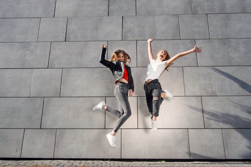 Two Beautiful Teenage Girlfriends Jump and Having Fun Near Grey ...