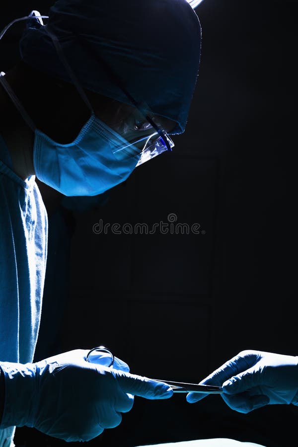 Two surgeons working and passing surgical equipment in the operating room, dark, close-up royalty free stock images