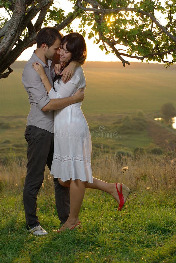 Two sweethearts kissing under tree at sunset