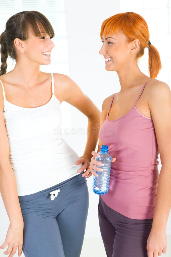 Two young women dressed sportswear talking. One of them holding water bottle. Two young women dressed sportswear talking. One of them holding water bottle.
