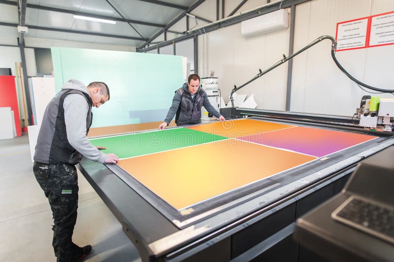 Two technicians works on CNC computer numerical control cutting machine stock images