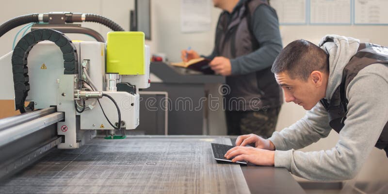 Two technicians works on CNC computer numerical control cutting machine royalty free stock image