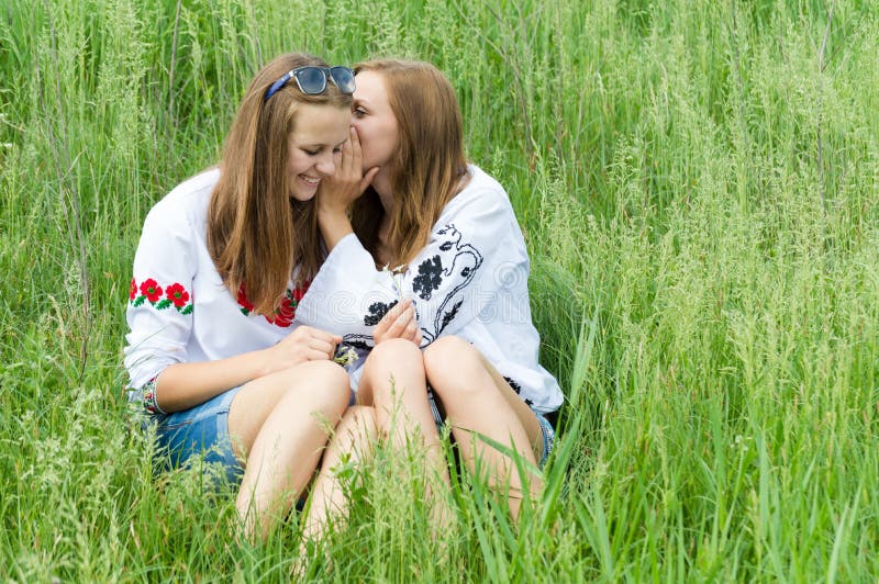 Two teen girl friends smiling sharing secret