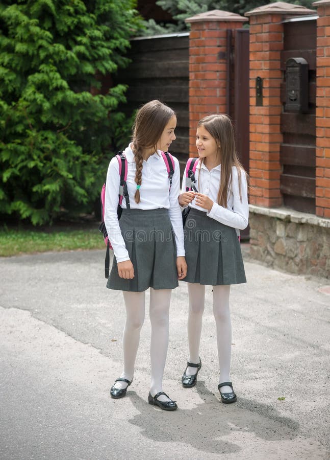 Two teenage girls walking on street and talking while going to school