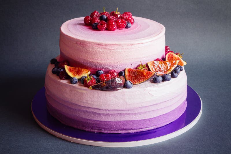 Two tiered purple cake with fruit on dark gray background