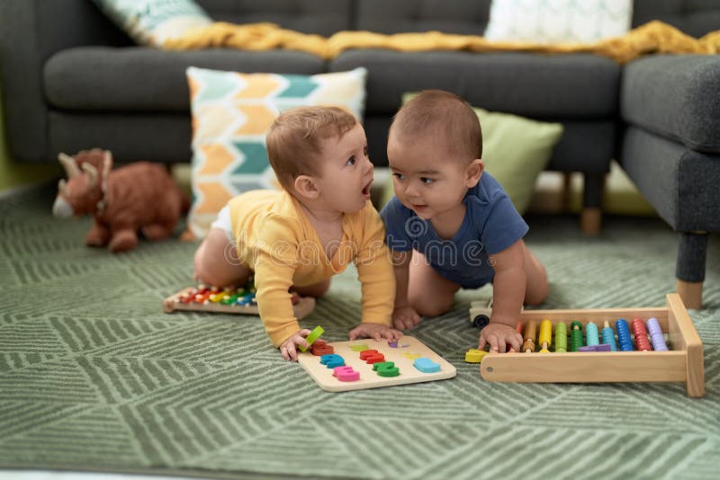 Two Toddlers Playing with Maths Toys Sitting on Floor at Home Stock