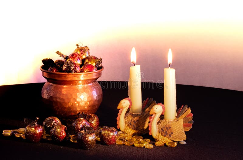 Two turkey candle holders with lit candles burning next to a copper filled with red and gold apples spilling out from it stock image Two turkey candle holders with lit candles burning next to a copper filled with red and gold apples spilling out from it stock image