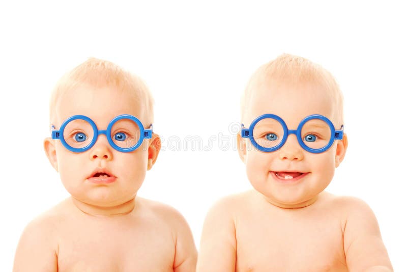 Two twins babies boys wearing glasses. One kid serious, the other child smiling. Young students. Isolated on white background