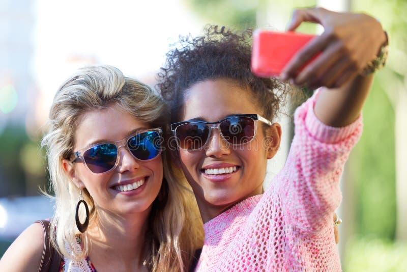 Two university girl students taking a selfie in the street.