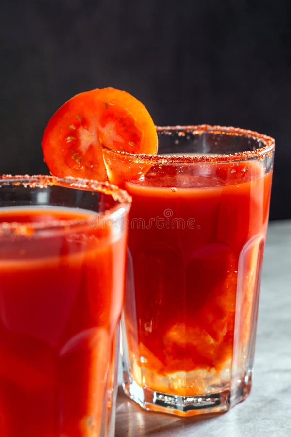 Two vegetable shaken cocktails in glass on dark grey background. Red tomato cocktail. Served with tomato slice. Vegan menu stock photography