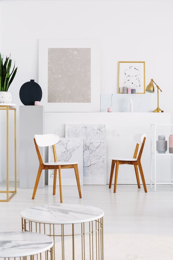 Two white wooden chairs, and tables with marble counter tops in white living room with maps and and art stock photos Two white wooden chairs, and tables with marble counter tops in white living room with maps and and art stock photos