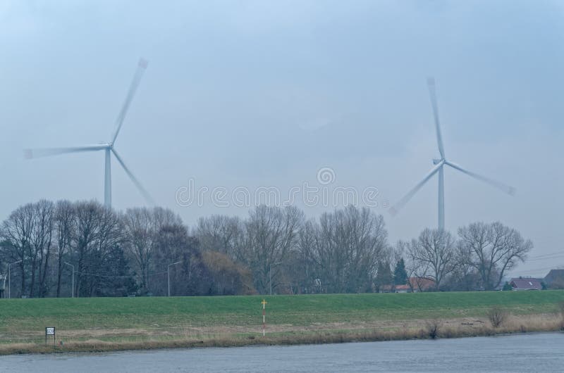 Two wind turbines rotate over trees. Two wind turbines under cloudy sky rotate over trees, Hamburg, Germany stock image Two wind turbines rotate over trees. Two wind turbines under cloudy sky rotate over trees, Hamburg, Germany stock image