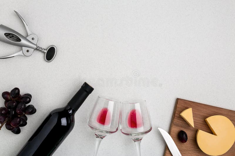 Two wine glasses with red wine,bottle of red wine and cheese on white background.Horizontal view from the top.