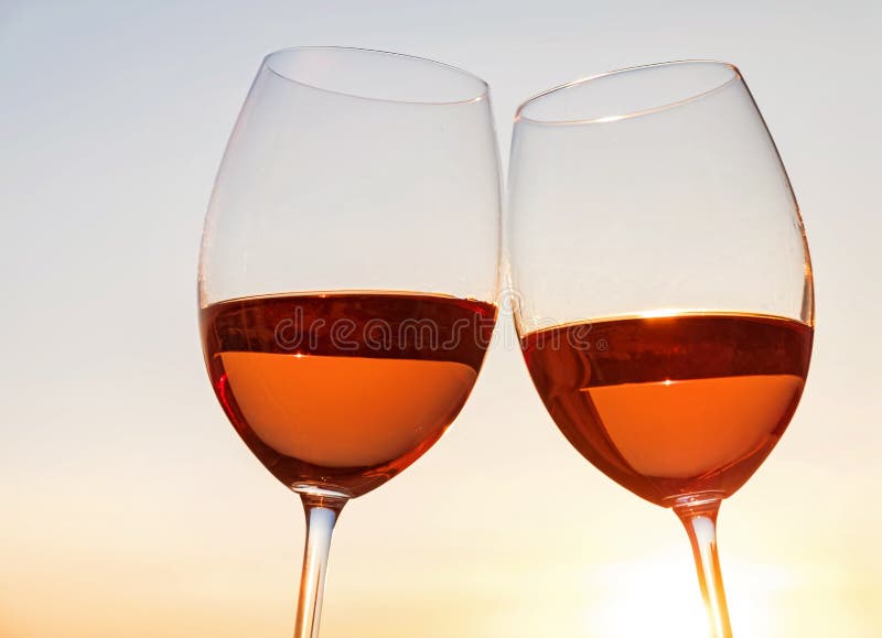 Two wine glasses on the sky background at sunset light.