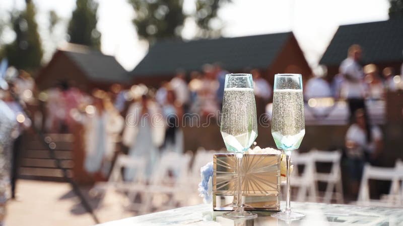 Two wine glasses with sparkling champagne on wedding ceremony table next to rings.