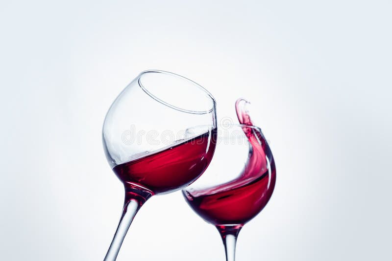 Two wine glasses in toasting gesture with big splashing.