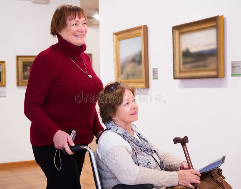 Zrelé ženy a pozitívne senior priateľ zdravotne postihnutých v art gallery.