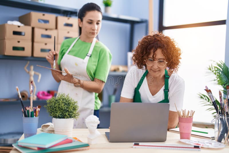 Two Women Artists Drawing on Notebook Using Laptop at Art Studio Stock