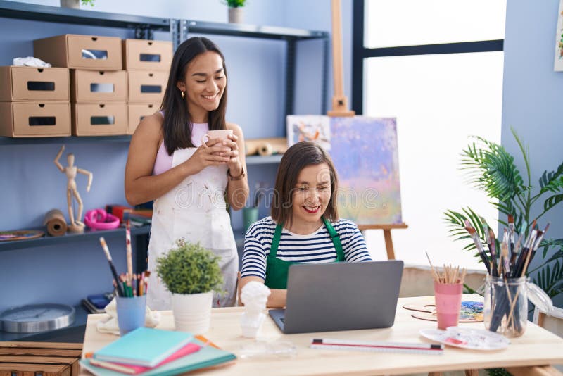 Two Women Artists Using Laptop Drinking Coffee at Art Studio Stock