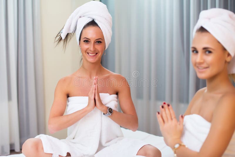 Two women in bathrobes with towels friends relaxing home spa.