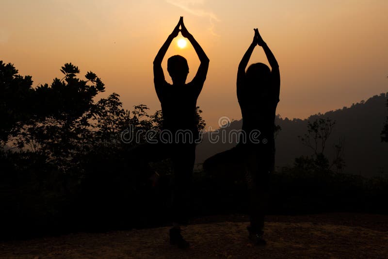 Two Women Doing Yoga Tree Pose in Silhouette during Sunrise Stock Image