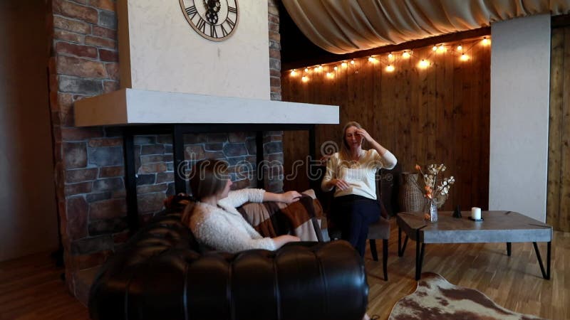 Two women engage in deep conversation in a cozy indoor setting with warm lighting and rustic decor stock video footage