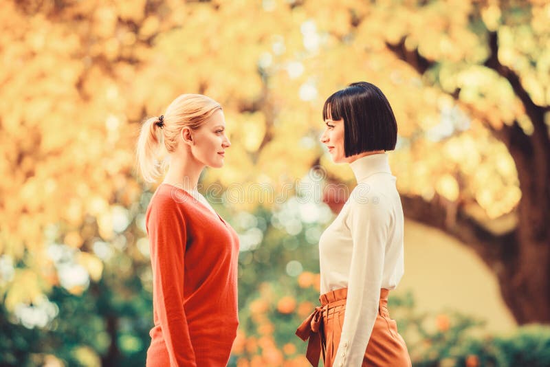 Two women are facing each other. girls looking into each others eyes. female friendship. walking in sunny park. best