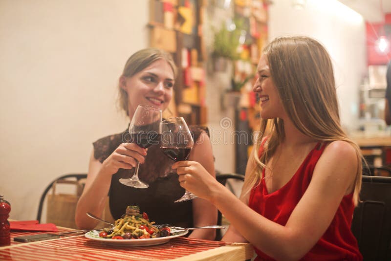 Two Women Holding Long-stem Wine Glasses With Red Liquid stock images