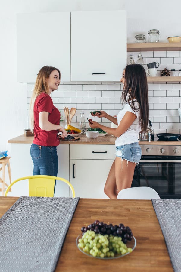 Two Women in Kitchen Cooking Talking Preparing Food. Stock Photo