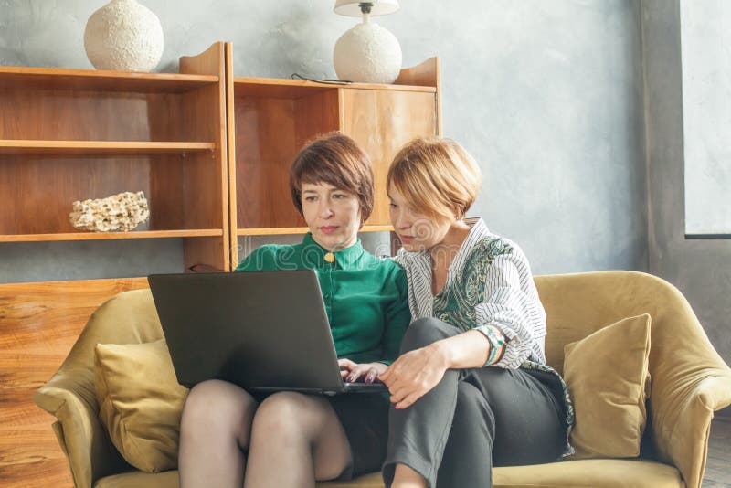 Two women with laptop indoors women 40s and 60s years old royalty free stock photo Two women with laptop indoors women 40s and 60s years old royalty free stock photo