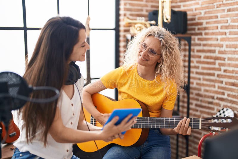 Two Women Musicians Playing Classical Guitar Looking Touchpad at Music Studio Stock Photo