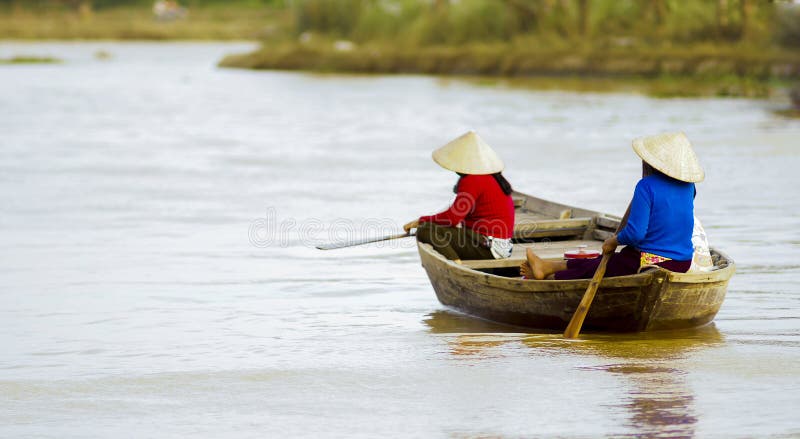 Two women row a boat on Thu Bon river