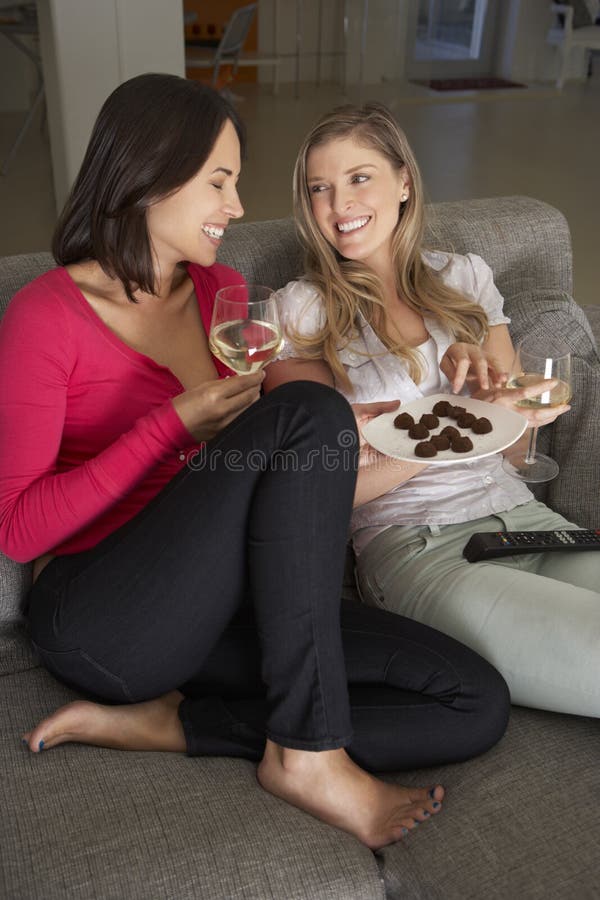 Two Women Sitting On Sofa Watching TV Drinking Wine stock images Two Women Sitting On Sofa Watching TV Drinking Wine stock images