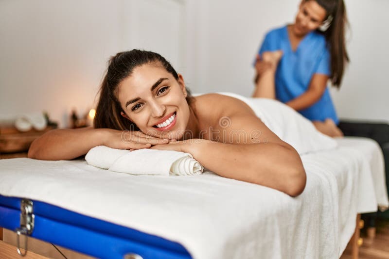 Two Women Therapist And Patient Having Massage Session Massaging Legs