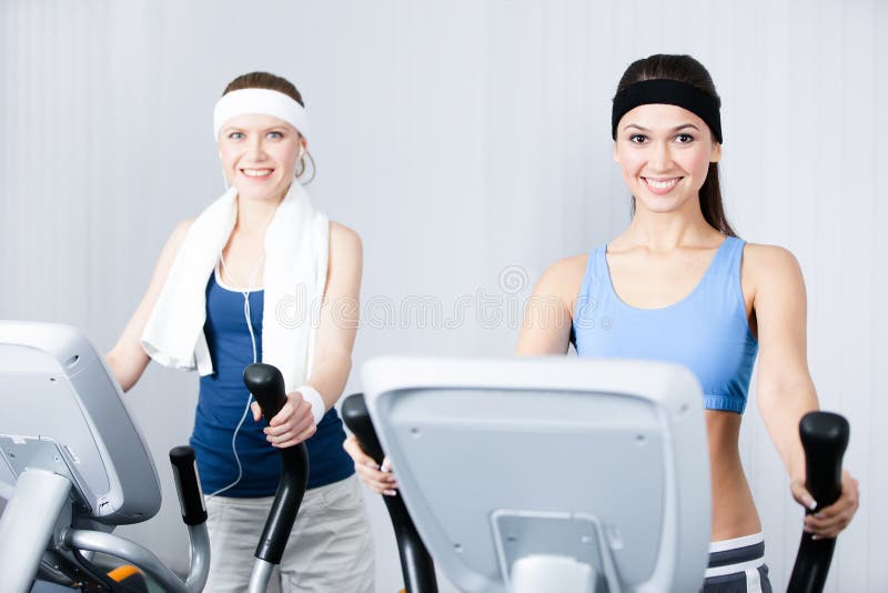 Two young women in sports wear training on training apparatus in gym. Two young women in sports wear training on training apparatus in gym