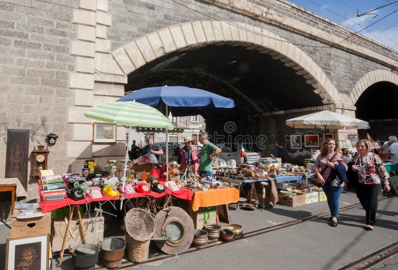 Two women walking past antique market stands with old phones, vintage stuff, flea market furniture royalty free stock photography Two women walking past antique market stands with old phones, vintage stuff, flea market furniture royalty free stock photography