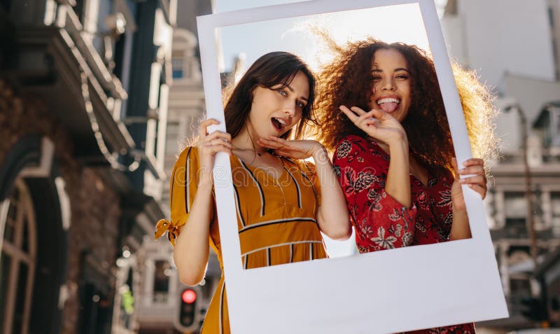Female friends posing with a blank picture frame royalty free stock photos Female friends posing with a blank picture frame royalty free stock photos