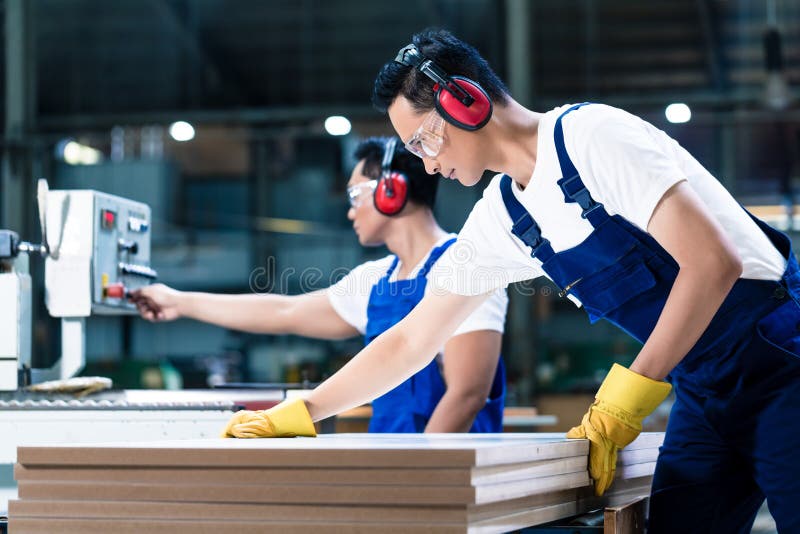 Two wood workers in carpentry cutting boards