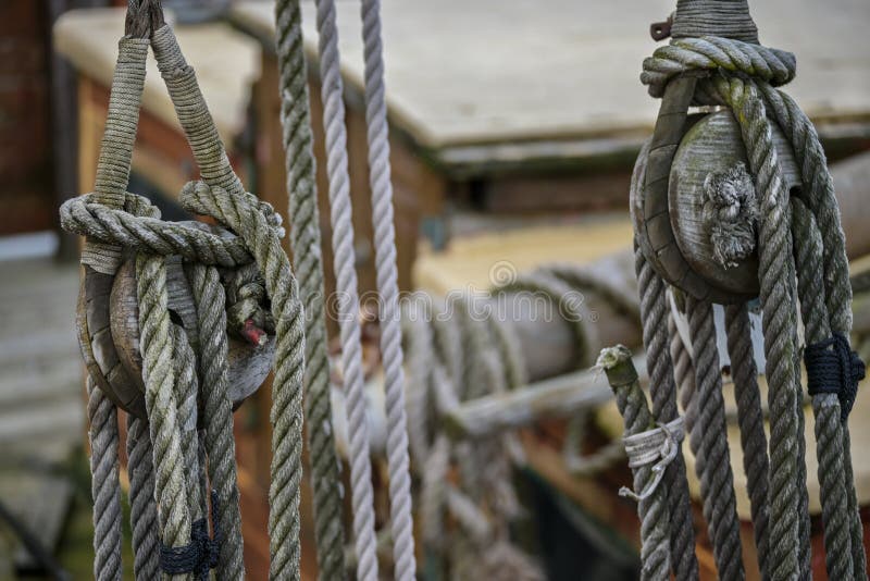 Two wooden pulley blocks with weathered ropes on an historic sailing boat, selected focus, narrow depth of field
