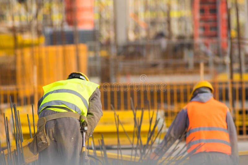 Two Builders in Yellow and Orange at the Construction Site Stock Photo