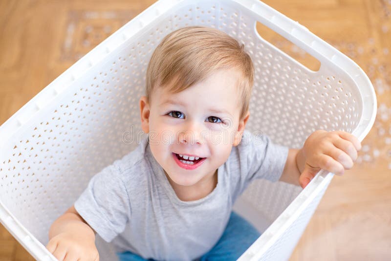 Two Year Old Boy Sitting in a Laundry Basket and Playing Stock Photo