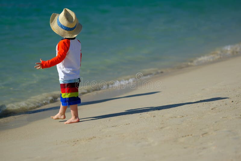 Two year old toddler boy walking on beach stock photography