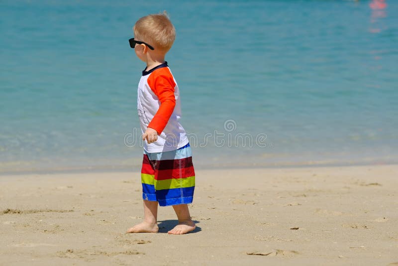 Two year old toddler boy walking on beach stock images