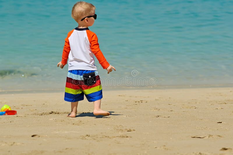 Two year old toddler boy walking on beach stock photos