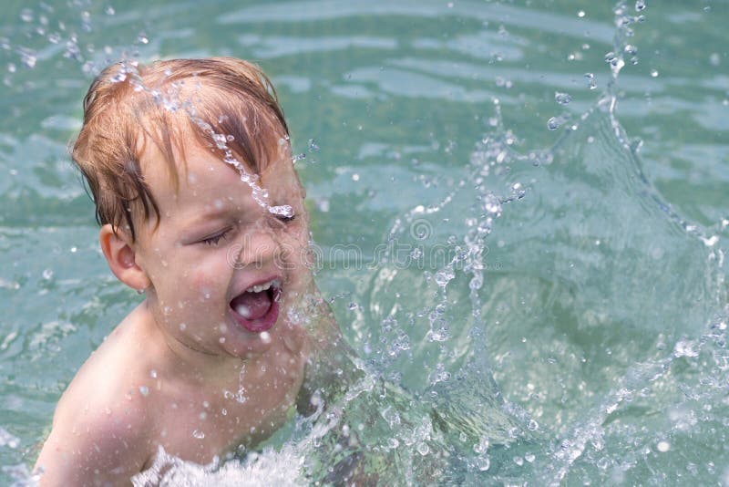 Two Years Old Boy is Splashing the Water in the Swimming Pool Stock
